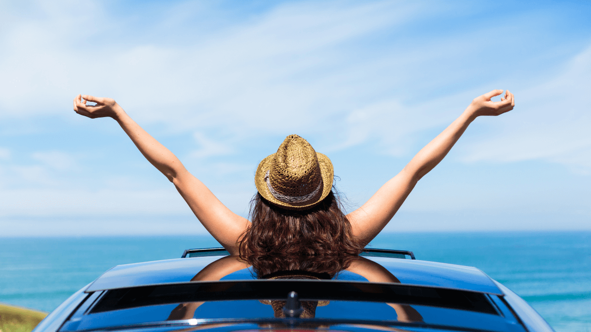 Adventurous young woman in a wide-brimmed hat stands confidently in the back of a pickup truck, embracing the liberating spirit of solo travel in her 20s.
