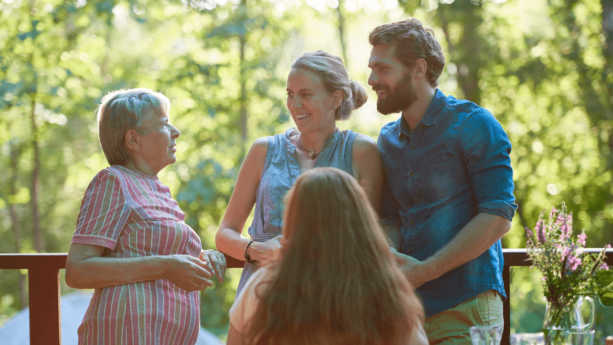 An elderly woman is chatting happily with a couple and a little girl, emphasizing the importance of keeping in touch with family.