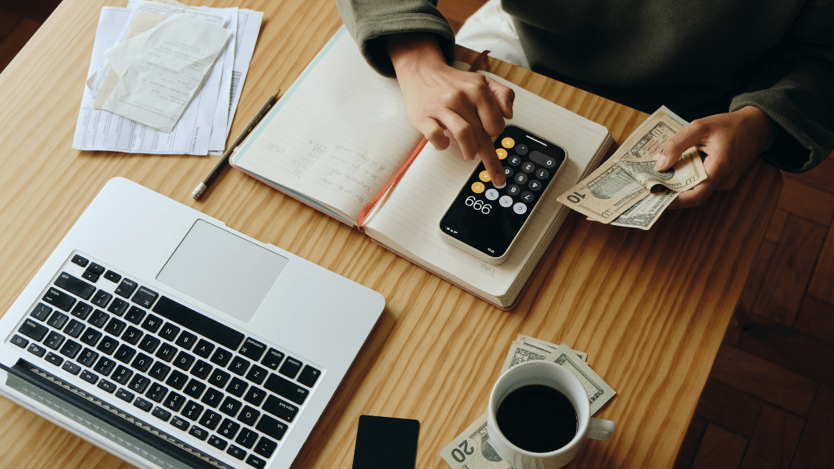 A laptop, a calculator, money and some bills emphasizes the importance of financial management when living alone.