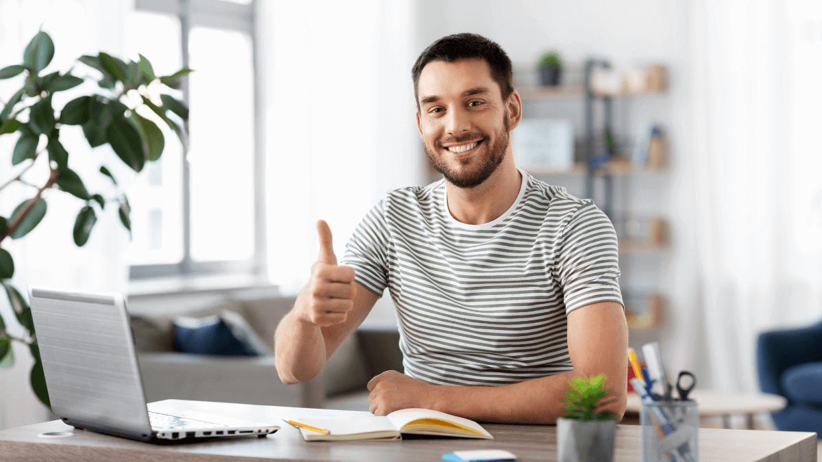 A joyful young man celebrates success, expressing happiness with the 'Ok' symbol, thriving in the experience of living alone in his 20s.